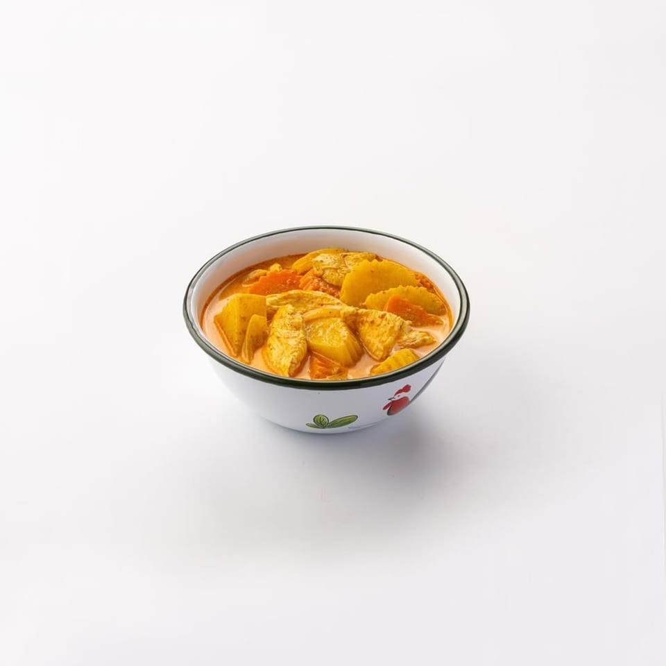 Skye Thai yellow curry with chicken, potatoes, and carrots in a white bowl with a rooster design.